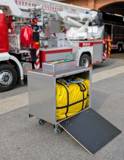 Feuerwehr Rollcontainer mit Zelt vor einem Löschfahrzeug auf dem Gelände der Feuerwehrwache.